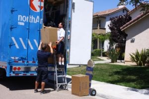 Two men loading big boxes in a moving truck